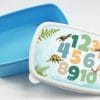 Auf dem Bild ist das Produkt: Brotdose mit Zahlen und Dinosauriern personalisiert mit Wunschnamen Schule Einschulungsgeschenk zum Preis von €16.90 abgebildet.