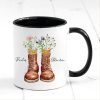 Auf dem Bild ist das Produkt: personalisierte Tasse mit Wanderstiefeln und Wildblumen Becher Geburtstagsgeschenk für einen Naturliebhaber mit Namen zum Preis von €17.90 abgebildet.