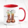 Auf dem Bild ist das Produkt: personalisierte Tasse mit Wanderstiefeln und Wildblumen Becher Geburtstagsgeschenk für einen Naturliebhaber mit Namen zum Preis von €17.90 abgebildet.
