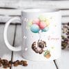 Auf dem Bild ist das Produkt: Tasse aus Keramik mit niedlichem Waschbär Motiv mit Korb und Luftballons, personalisiert mit Wunschnamen zum Preis von €16.9 abgebildet.