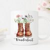 Auf dem Bild ist das Produkt: Tasse bedruckt mit Wanderstiefeln mit Wildblumen Gräsern und Wanderlust Kaffeetasse Geschenk zum Preis von €18.9 abgebildet.